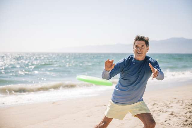 man playing frisbee at beach