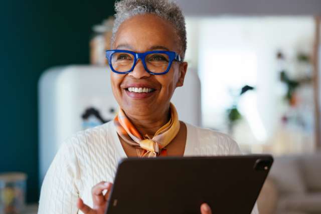 Middle-aged woman smiling while using tablet